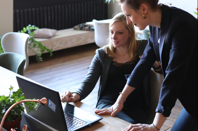 Büroszene zwei Frauen schauen auf einen Laptop